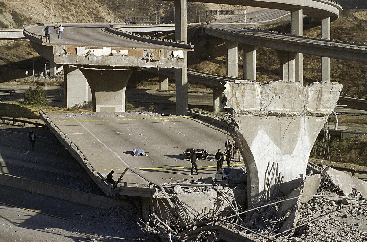 In this Jan. 17, 1994, file photo, the covered body of Los Angeles Police Officer Clarence Wayne Dean lies near his motorcycle which plunged off the State Highway 14 overpass that collapsed onto Interstate 5, after a magnitude-6.7 Northridge earthquake in Los Angeles.(AP Photo/Doug Pizac)