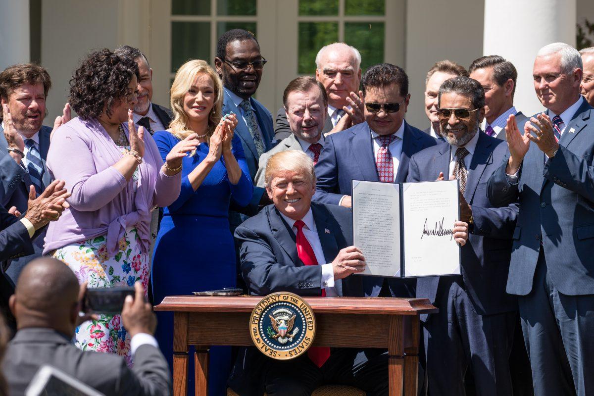 Trump signs an executive order titled “Establishment of a White House Faith and Opportunity Initiative” at the National Day of Prayer in the Rose Garden of the White House on May 3, 2018. (Samira Bouaou/The Epoch Times)