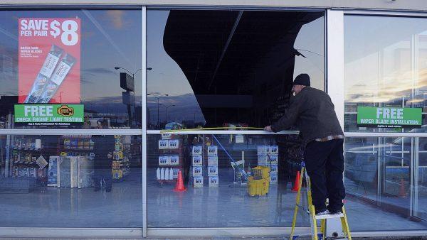 Dennis Keeling, of Instant Services, measures for a broken window at an auto parts store following an earthquake in Anchorage, Alaska, on Nov. 30, 2018. (Mike Dinneen/AP)