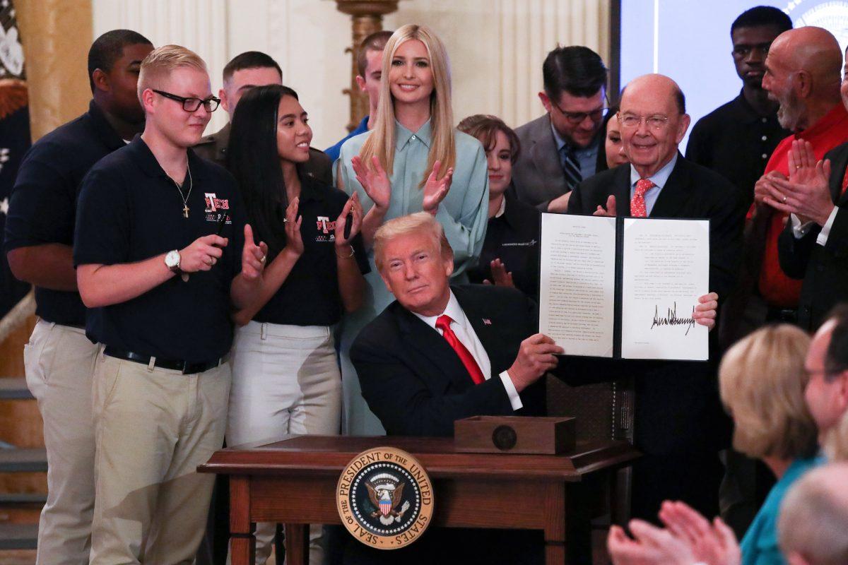 President Donald Trump signs an executive order during the "Pledge to America’s Workers" event on July 19, 2018. (Samira Bouaou/The Epoch Times)