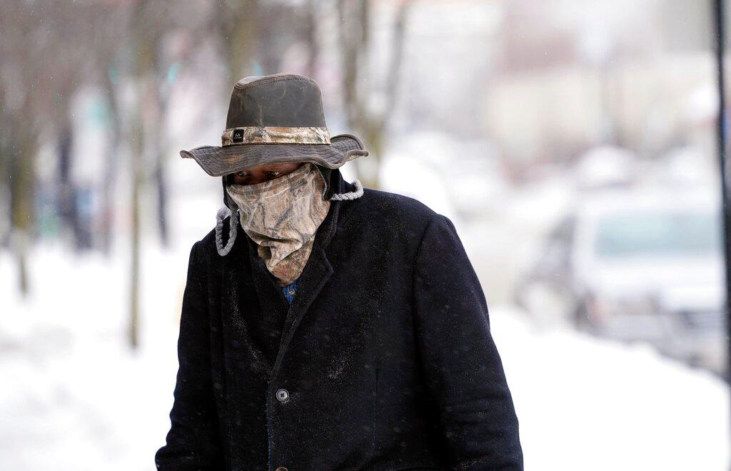 Marvin Hooks wears a face mask to protect him from the cold as he walks on North Street in Pittsfield, Mass., Monday, Jan. 21, 2019. Bitter cold and gusty winds swept across the eastern U.S. Monday with falling temperatures replacing the weekend's falling snow. (Ben Garver/The Berkshire Eagle via AP)