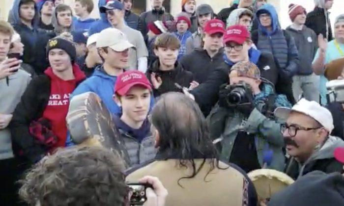 Nick Sandmann, wearing a "Make America Great Again" hat, stands looking at Nathan Phillips, a Native American and anti-President Donald Trump activist, after Philipps approached the Covington Catholic High School student in Washington on Jan. 18, 2019. (Survival Media Agency via AP)
