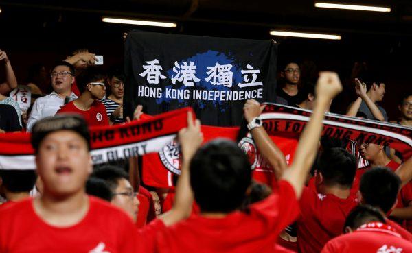 During the Hong Kong versus Malaysia AFC Asian Cup Qualifiers in Hong Kong, China on Oct. 10, 2017, Hong Kong fans hold a protest banner and turn their backs during the Chinese national anthem. (Bobby Yip/Reuters)