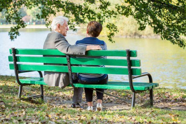 A couple sits on a bench by the water. (Paul Clifton/Shutterstock)