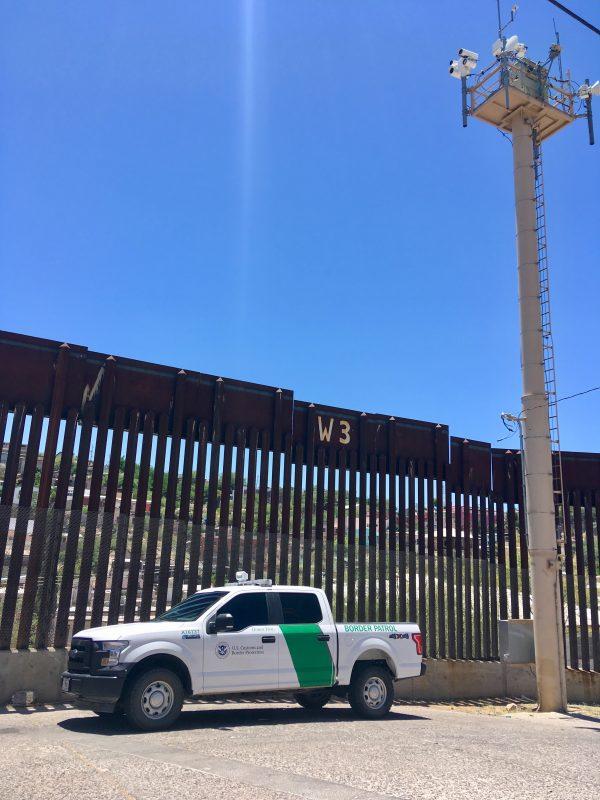 A Border Patrol truck sits next to the fence and a surveillance tower at the U.S.–Mexico border in Nogales, Ariz., on May 23, 2018. (Samira Bouaou/The Epoch Times)