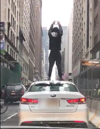 An unknown assailant gestures on the Uber roof on Jan. 18, 2019. (Screenshot/NYP)