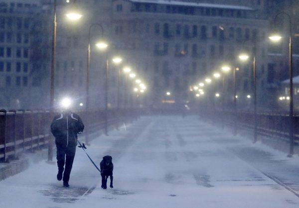 A runner and his dog brave frigid conditions while making their way east across the Stone Arch Bridge in Minneapolis, on Jan. 24, 2019. (David Joles/Star Tribune via AP)