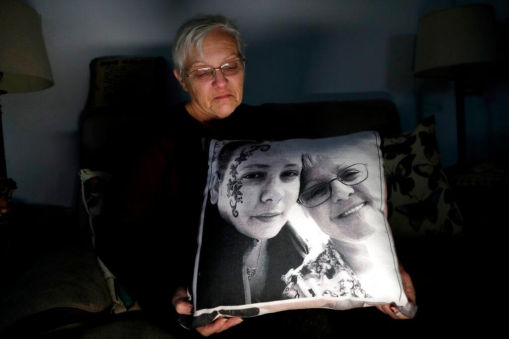 In a photo taken Friday, Jan. 18, 2019, Deborah Fuller poses for a photograph for The Associated Press with a pillow showing a photo of her late daughter, Sarah Fuller, left, who passed of a prescription drug overdose, and her during an interview in her home in West Berlin, N.J. The trial of a Insys Therapeutics Inc. founder John Kapoor, who accused of scheming to bribe doctors into prescribing a powerful painkiller, is putting a spotlight on the nation's deadly opioid crisis. (AP Photo/Julio Cortez)