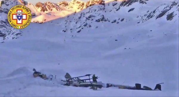 A rescuer stands next to the debris of a helicopter after a midair collision between a small tourist airplane and a helicopter carrying skiers to a glacier in the northwestern region of Val d'Aosta, on Jan 25, 2019. (Soccorso Alpino e Speleologico via AP)