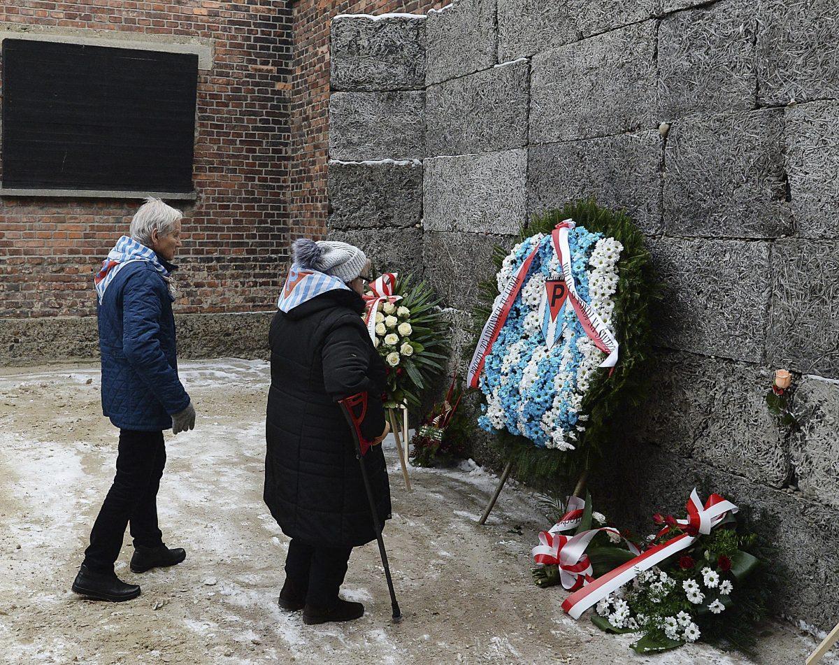 Former prisoners place candles and flowers at the Death Wall marking the 74th anniversary of the liberation of KL Auschwitz-Birkenau, in Oswiecim, Poland, on Jan. 27, 2019.(AP Photo/Czarek Sokolowski)