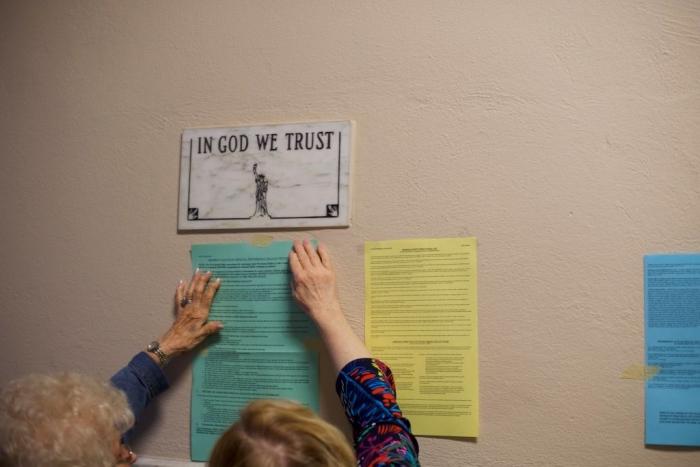 Election officials affix voting notices to the wall, below a plaque that states 'IN GOD WE TRUST,' at the Hazleton City Hall on May 15, 2018, in Hazleton, Pennsylvania. (Mark Makela/Getty Images)