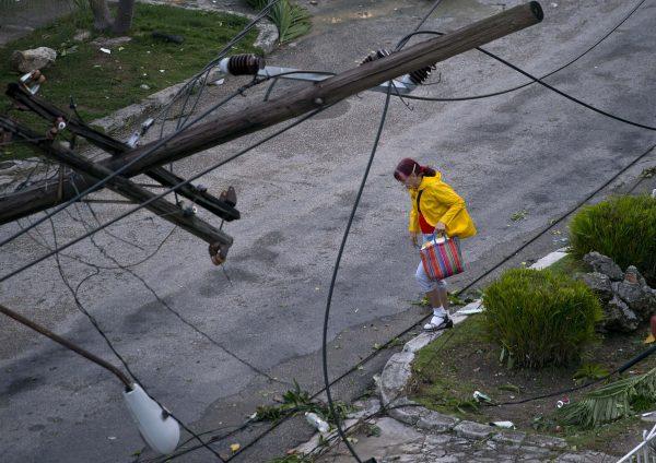 A woman walks under a lamp post toppled by a tornado in Havana, Cuba, on Jan. 28, 2019. (Ramon Espinosa/AP)