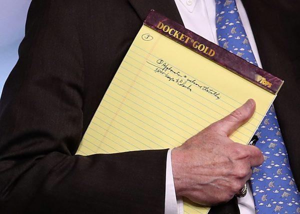 With handwritten notes on a legal pad, National Security Adviser John Bolton listens to questions from reporters during a press briefing at the White House in Washington, on Jan. 28, 2019. (Win McNamee/Getty Images)