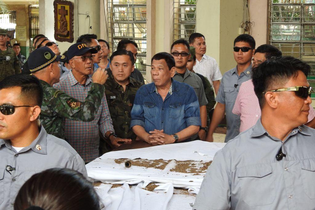 Philippine President Rodrigo Duterte (C) and Defense Secretary Delfin Lorenzana (2nd L, with spectacles) listen to national police chief Director General Oscar Albayalde (L, in camouflage) as they inspect the damage area of a catholic cathedral in Jolo town, sulu province, in southern island of Mindanao on January 28, 2019, a day after two explosions tore through the cathedral. (Nickee Butlangan/AFP/Getty Images)
