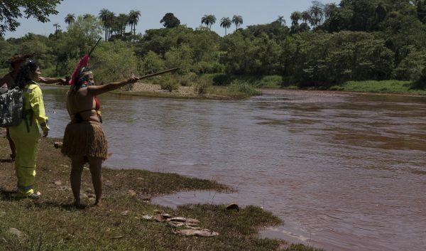 A Pataxo Ha-ha-hae indigenous woman points toward the Paraopeba River as she speaks to a member of the Brazilian Environmental Institute (IBAMA) in her village, in Brumadinho, Brazil, on Jan. 29, 2019. (Leo Correa/AP)