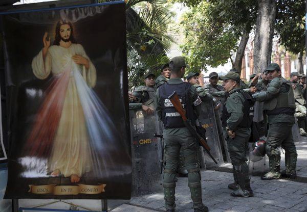 Venezuelan Bolivarian National Guardsmen line up near a Divine Mercy Jesus Christ poster outside the National Assembly in Caracas, Venezuela, on Jan. 29, 2019. (Rodrigo Abd/AP Photo)