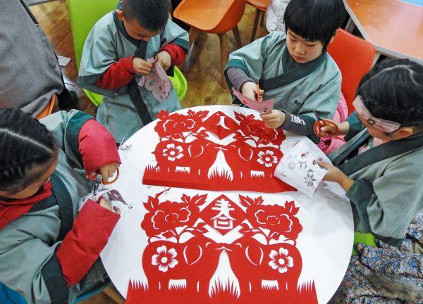 Children learn traditional paper cutting with festive red paper, the Year of the Pig, in Lianyungang, Jiangsu Province, China on Jan. 30, 2019. (STR/AFP/Getty Images)