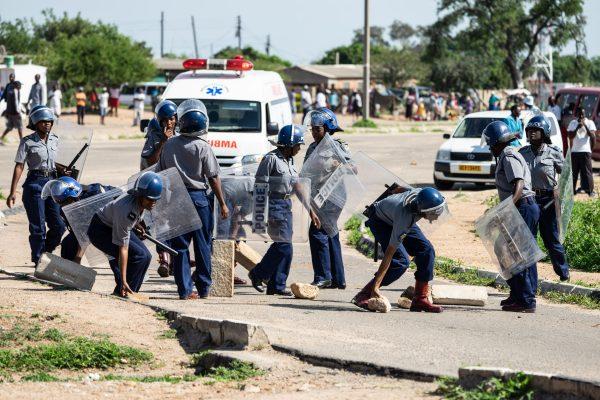 Police officers make way for an ambulance by removing stones from a barricade during a demonstration against the doubling of fuel prices on Jan. 14, 2019, in Bulawayo, Zimbabwe. (Zinyange Auntony/AFP/Getty Images)