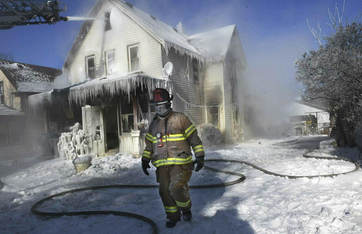A firefighter walks past an ice-encrusted home after an early morning house fire in St. Paul, Minn. on Jan. 30, 2019. (Jean Pieri/Pioneer Press via AP)