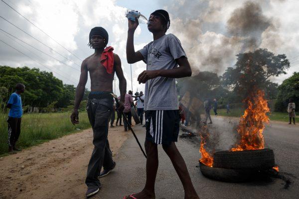Men stand next to burning tires as angry demonstrators protests fuel price hikes barricade the main route to Zimbabwe's capital Harare from Epworth township on Jan. 14, 2019. (Jekesai Njikizana/AFP/Getty Images)