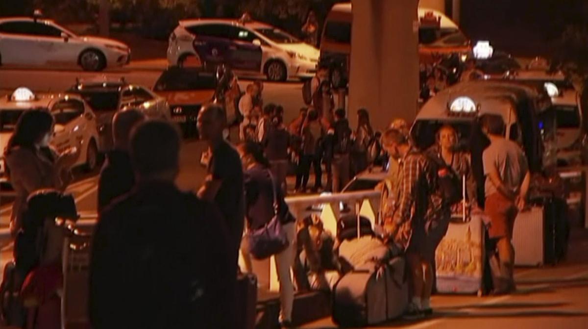 In this image made from a video, taken on Feb. 2, 2019, travelers stay outside Brisbane International Airport after their evacuation from the airport in Brisbane, Australia. (Australian Broadcasting Corporation via AP)
