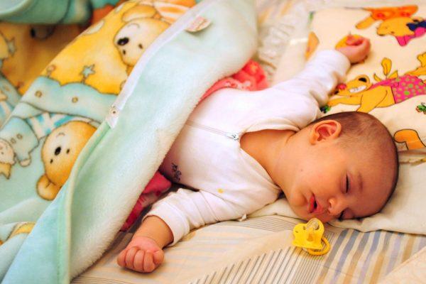 A baby sleeps with her pacifier next to her. (Hamed Saber/Flickr/CC BY 2.0)