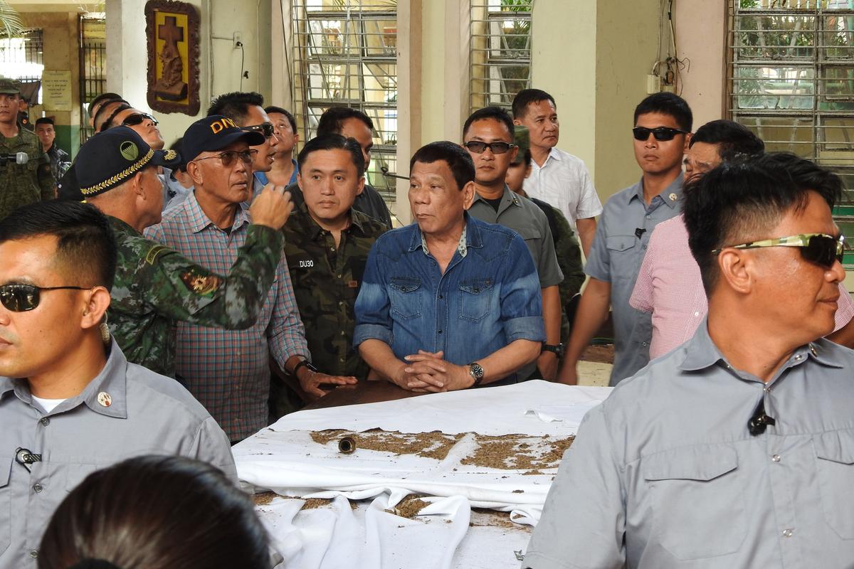 Philippine President Rodrigo Duterte (C) and Defense Secretary Delfin Lorenzana (2nd L, with spectacles) listen to national police chief Director General Oscar Albayalde (L, in camouflage) as they inspect the damage area of a catholic cathedral in Jolo town, sulu province, in southern island of Mindanao on Jan. 28, 2019