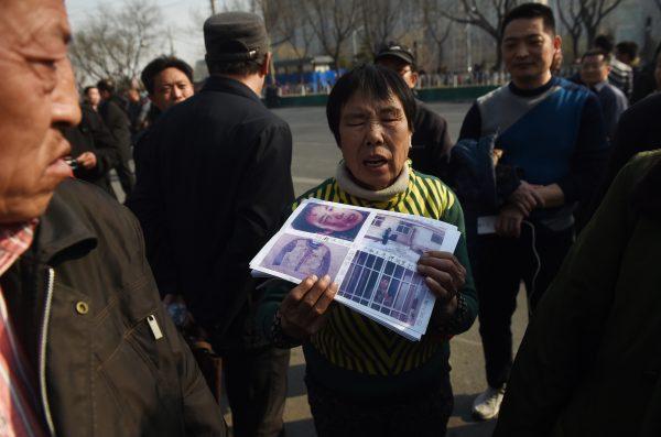 A petitioner holds photos of evidence in her grievance against local officials outside a government petition office in Beijing on March 2, 2016. (Greg Baker/AFP/Getty Images)