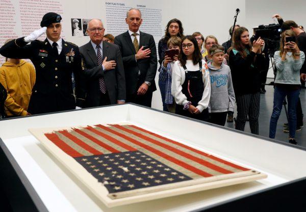 U.S. ambassador Pete Hoekstra unveils an American flag from a vessel during Normandy landing. Kunsthal Museam in Rotterdam, Netherlands, Feb. 4, 2019. (Reuters/Eva Plevier)