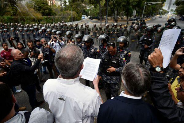 Venezuela's Central University (UCV) professor Juan Carlos Apitz (C) reads an amnesty proposal of opposition leader and self-proclaimed "acting president" Juan Guaido to members of the Bolivarian National Police (PNB), in Caracas. (Luis Robayo/AFP/Getty Images)