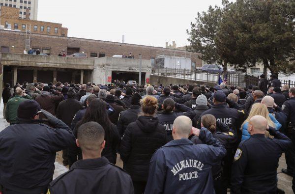 Hundreds of police officers fill in the back entrance to the Medical Examiner's office and salute while the casket containing the body of slain officer Matthew Ritter is moved from the hearse in Milwaukee, Wis., on Feb. 6, 2019. (Rick Wood/Milwaukee Journal-Sentinel via AP)