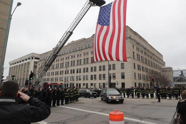 The Milwaukee Fire Department raises a flag as the hearse containing the casket of officer Matthew Ritter drives under in Milwaukee, Wis., on Feb. 6, 2019 (James B. Nelson/Milwaukee Journal-Sentinel via AP)