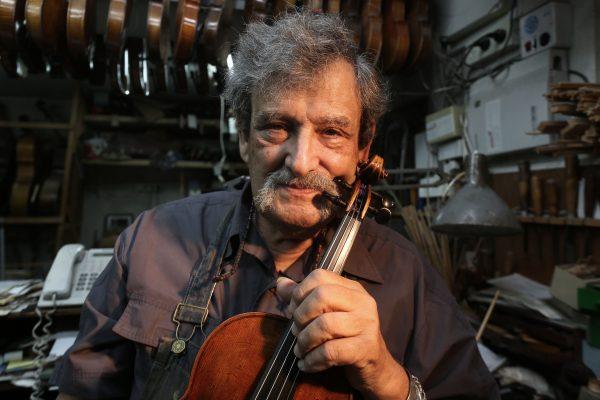 Israeli violin maker Amnon Weinstein holds a violin which he named the "Auschwitz Violin" since it belonged to a Jewish man imprisoned at the Auschwitz concentration camp during the Second World war at his workshop in Tel Aviv on July 15, 2016. (Menahem Kahana/AFP/Getty Images)