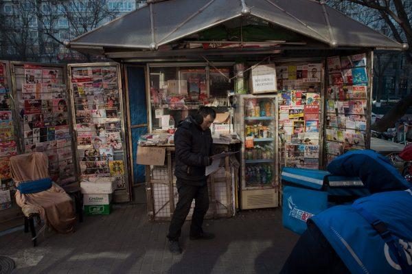 A man reads a newspaper in front of a newspaper and magazine stand in Beijing in this file photo. (Nicolas Asfouri/AFP/Getty Images)
