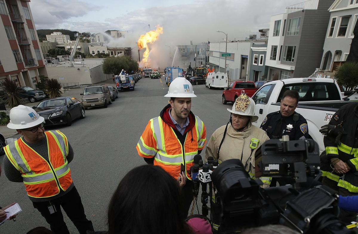 San Francisco fire chief Joanne Hayes-White, second from right, listens as Pacific Gas and Electric spokesperson Paul Doherty, center, speaks to reporters about a fire on Geary Boulevard in San Francisco, Wednesday, Feb. 6, 2019. (AP Photo/Jeff Chiu)