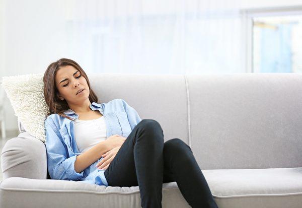 Illustration - Shutterstock | <a href="https://www.shutterstock.com/image-photo/young-woman-suffering-abdominal-pain-home-585974285">Africa Studio</a>
