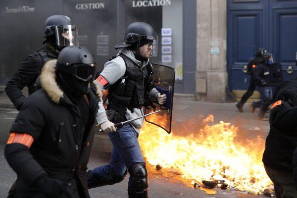 Riot police run past burning dustbins set on fire by yellow vest protesters as they keep pressure on French President Emmanuel Macron's government, for the 13th straight weekend of demonstrations, in Paris, France, on Feb. 9, 2019. (Kamil Zihnioglu/AP Photo)
