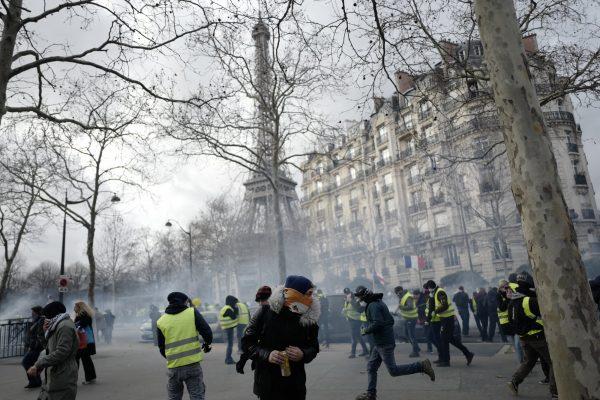 Yellow vest protesters run away from tear gas fired by riot police as they keep pressure on French President Emmanuel Macron's government, for the 13th straight weekend of demonstrations, during a demonstration in Paris, France, on Feb. 9, 2019. (Kamil Zihnioglu/AP Photo)