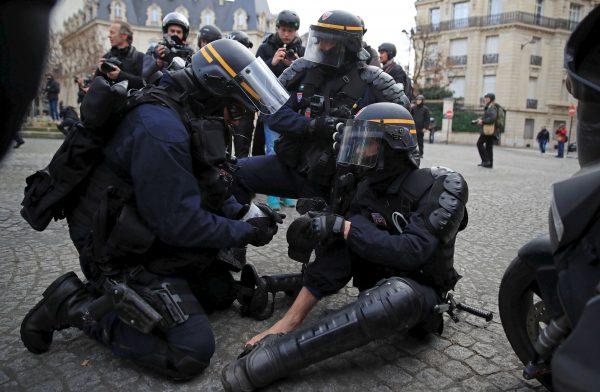 An injured policeman in riot gear is given help during a demonstration by the yellow vests in Paris on Feb. 9, 2019. (Gonzalo Fuentes/Reuters)