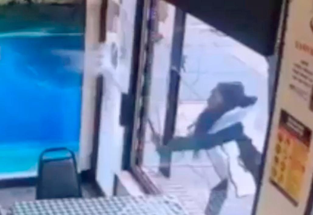 In this Jan. 15, 2019 image taken from surveillance video, a woman smashes the windows of "Back Home Restaurant" in the Bronx borough of N.Y. (New York City Police Department via AP)