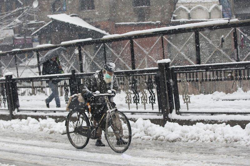 An elderly Kashmiri man pushes his cycle on a snow-covered road in Srinagar. Avalanches and landslides killed 11 people in the region. (Dar Yasin/AP Photo)