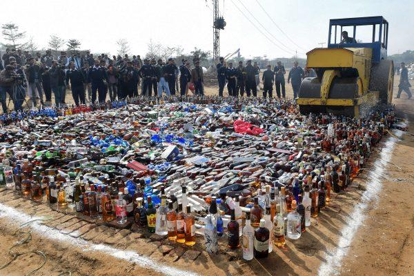 Pakistani custom officials look on as a steamroller smash bottles of alcohol at the Wagah border between Pakistan and India on Jan. 26, 2019. (Arif AliI/AFP/Getty Images)