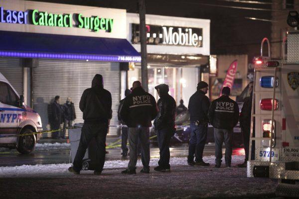 Investigators look over the area after a few New York City police officers were shot while responding to a robbery at a T-Mobile store in the Queens borough of N.Y., on Feb. 12, 2019. (AP Photo/Kevin Hagen)