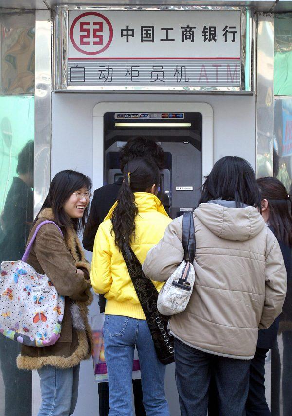 A group of young women wait their turn at an automated-teller machine (ATM) outside a bank in Beijing on March 11, 2004. China's state banks can ill afford an explosion in bad debt, as they are estimated to already be saddled with at least three trillion yuan in non-performing loans (NPL) in 2004, or one quarter the size of the entire national economy. (Goh Chai Hin/AFP/Getty Images)