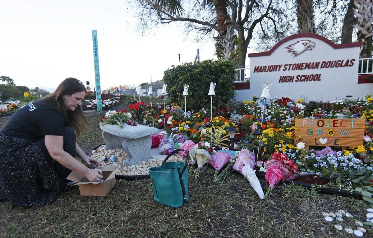 Suzanne Devine Clark, an art teacher at Deerfield Beach Elementary School, places painted stones at a memorial outside Marjory Stoneman Douglas High School during the one-year anniversary of the school shooting in Parkland, Fla., on Feb. 14, 2019. (Wilfredo Lee/AP Photo)