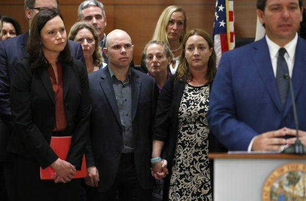 Ilan and Lori Alhadeff (C), the parents of Alyssa Alhadeff, who was killed in the Parkland, Fla., school shooting, hold hands as they listen to Florida Gov. Ron DeSantis during a news conference, on Feb. 13, 2019. (Wilfredo Lee/AP Photo)