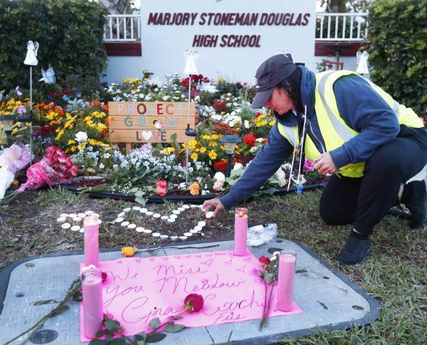 School crossing guard Wendy Behrend lights a candle at a memorial outside Marjory Stoneman Douglas High School during the one-year anniversary of the school shooting,in Parkland, Fla. on Feb. 14, 2019. (Wilfredo Lee/AP Photo)