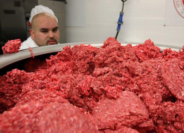 FILE—A worker at a meat packing facility monitoring ground beef as it passes through a machine that makes hamburger patties in San Francisco, on June 24, 2008. (Justin Sullivan/Getty Images)