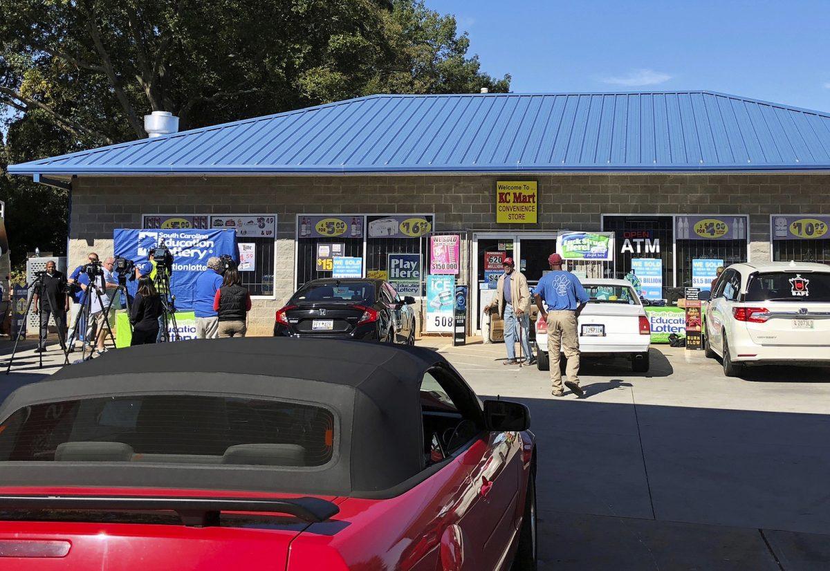 In this Oct. 24, 2018, file photo, media, left record people entering the KC Mart in Simpsonville, S.C., after it was announced the winning Mega Millions lottery ticket was purchased at the store. Officials confirmed on Feb. 14, 2019, that the winner of the $1.5 billion lottery has still not come forward. (Jeffrey Collins,/AP Photo,File)