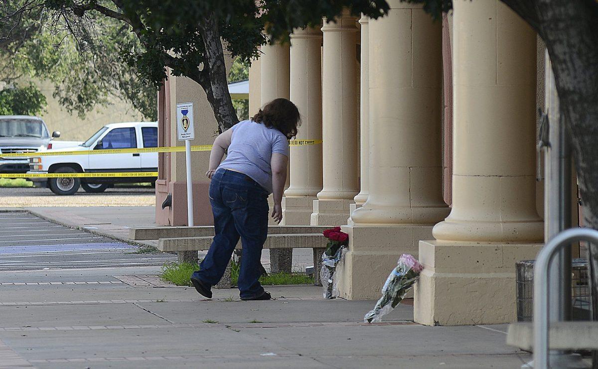 A woman places flowers at the entrance of the Clovis-Carver Public Library in Clovis, N.M., a day after a deadly shooting. (Adolphe Pierre-Louis/The Albuquerque Journal via AP, File)